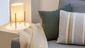 A cozy seating area with a lamp, a blanket, and two pillows on a couch. - Waou Best IV Madrid Rio (Madrid)