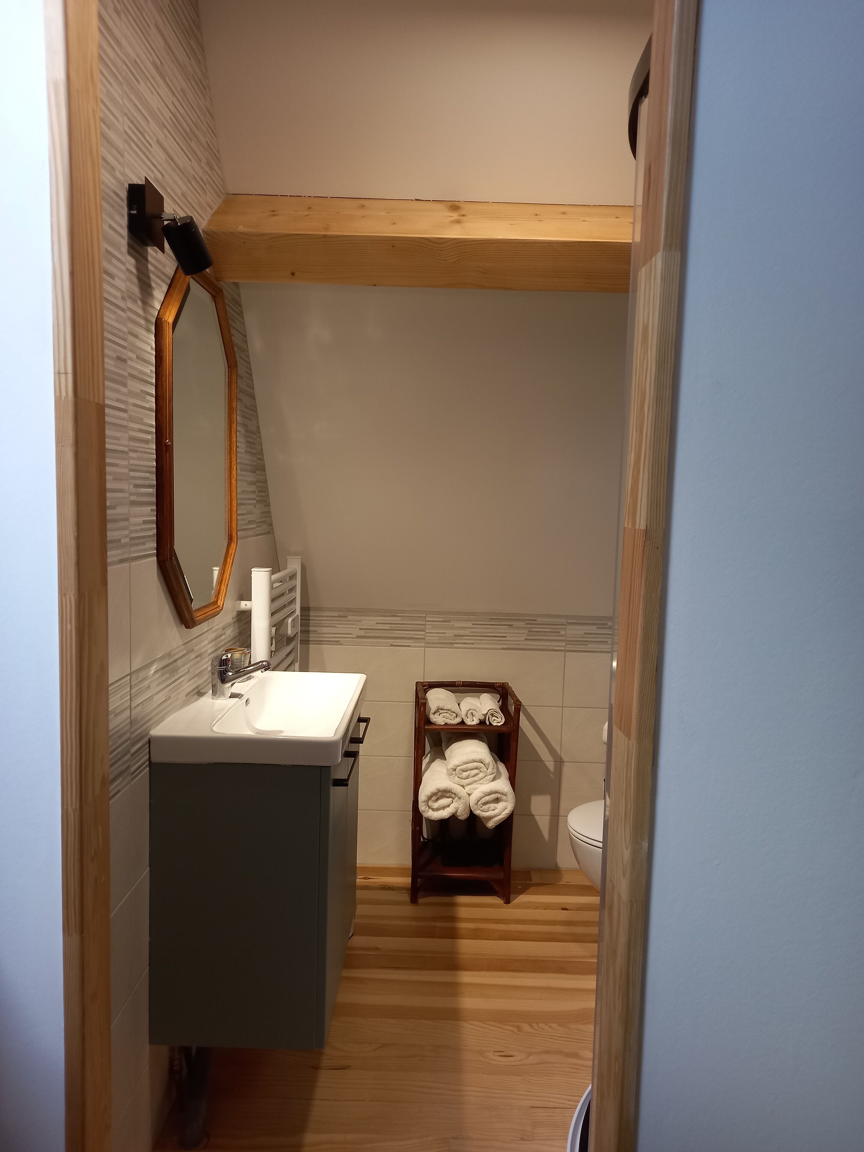 Une salle de bain avec un meuble-lavabo en bois, un miroir, un porte-serviettes et des toilettes.