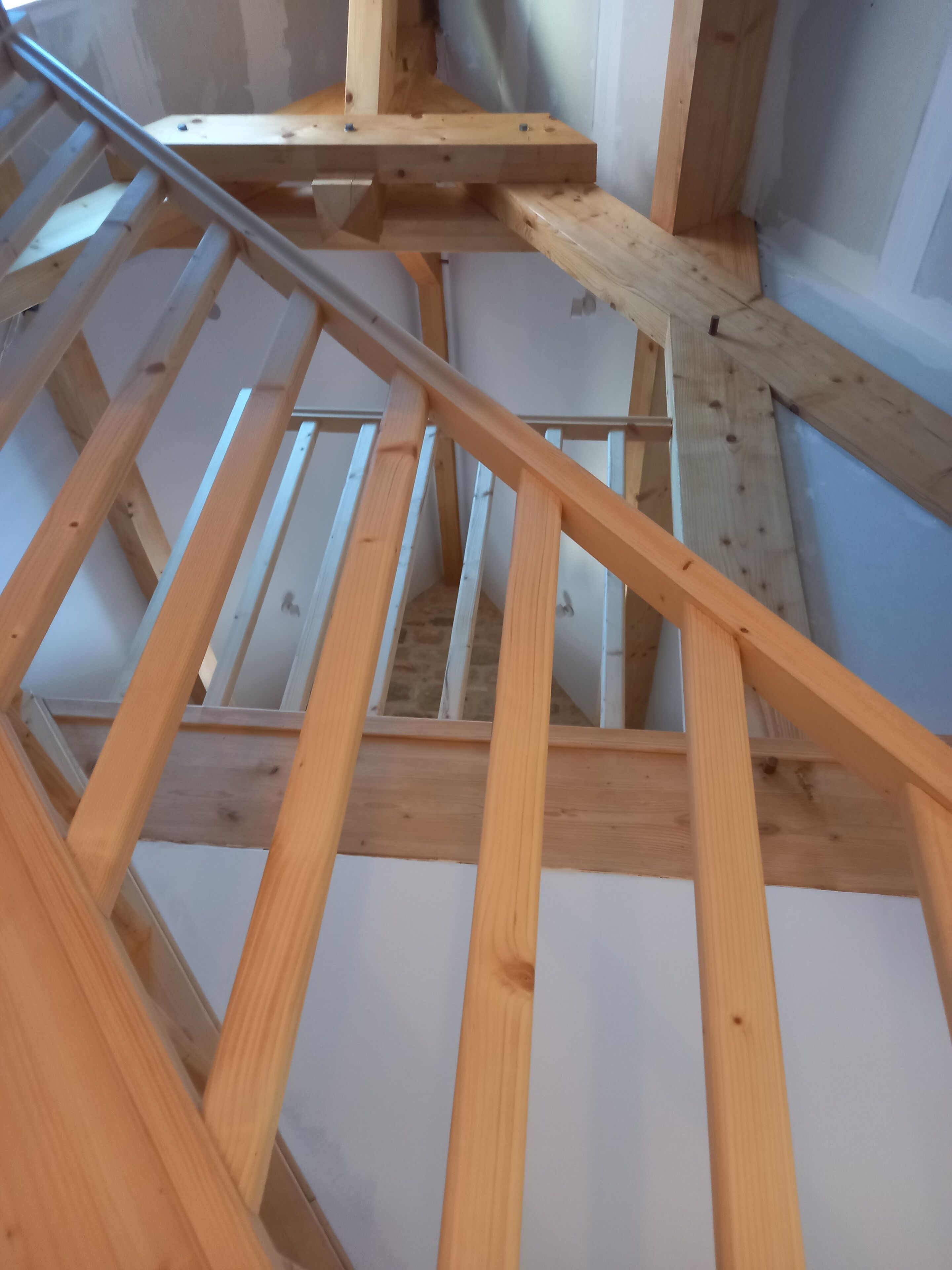 Un escalier en bois avec une rampe métallique, menant à l’étage supérieur.