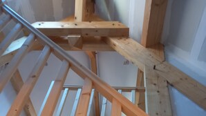 A wooden staircase with a metal handrail, leading to an upper floor.