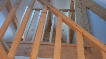 Un escalier en bois avec une rampe métallique, menant à l’étage supérieur.