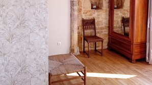 A room with a stone wall, a wooden chair, a mirror, and a hanging light fixture.