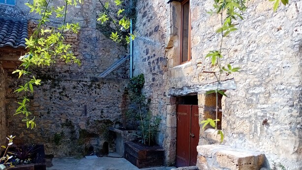 A courtyard with stone walls, a wooden door, and a window.