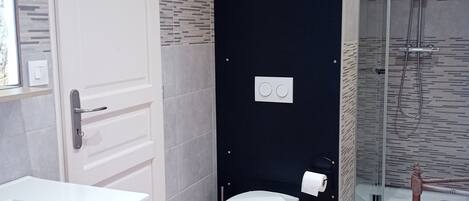 Une salle de bain avec un lavabo blanc, des toilettes et un espace douche.