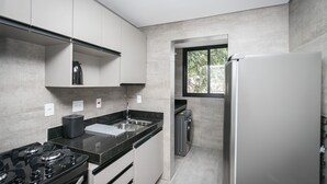 A modern kitchen with a gas stove, stainless steel sink, and a built-in oven. - Moderno apartamento 2 quartos (Belo Horizonte)