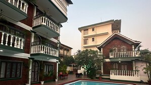 A swimming pool surrounded by multi-story buildings with balconies and potted plants. - Olive Zip Calangute Mira by Embassy Group (Calangute)