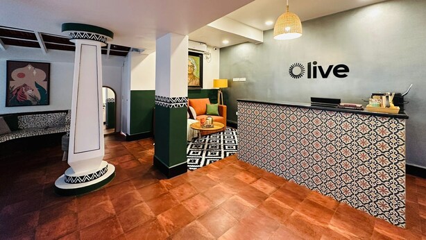 A reception area with a patterned floor, a reception desk, a sofa, and a hanging light fixture. - Olive Zip Calangute Mira by Embassy Group (Calangute)