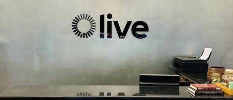A reception desk with a 'live' sign, patterned tiles, and a hanging light fixture.