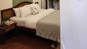 A bedroom with a bed, a nightstand, a wall-mounted mirror, and a door. - Olive Zip Calangute Mira by Embassy Group (Calangute)