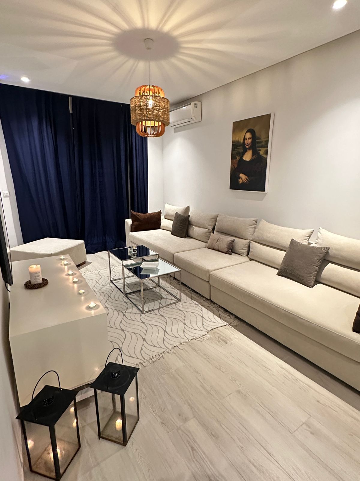 A modern living room with a beige sofa, a glass coffee table, and a patterned rug.