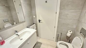 Ein modernes Badezimmer mit Waschbecken, Toilette und Duschbereich in Weiß.