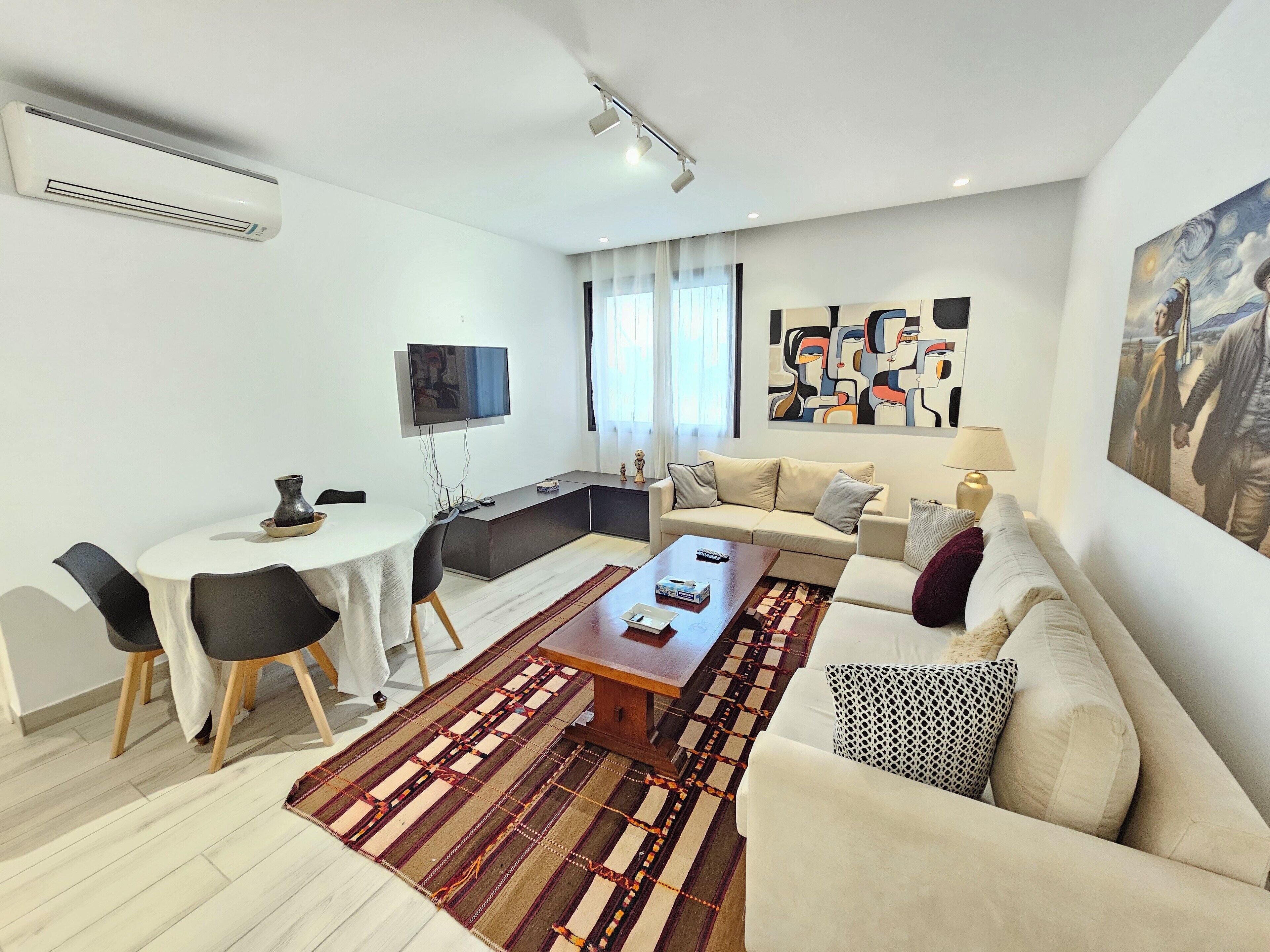A modern living room with a sofa, coffee table, and dining area.