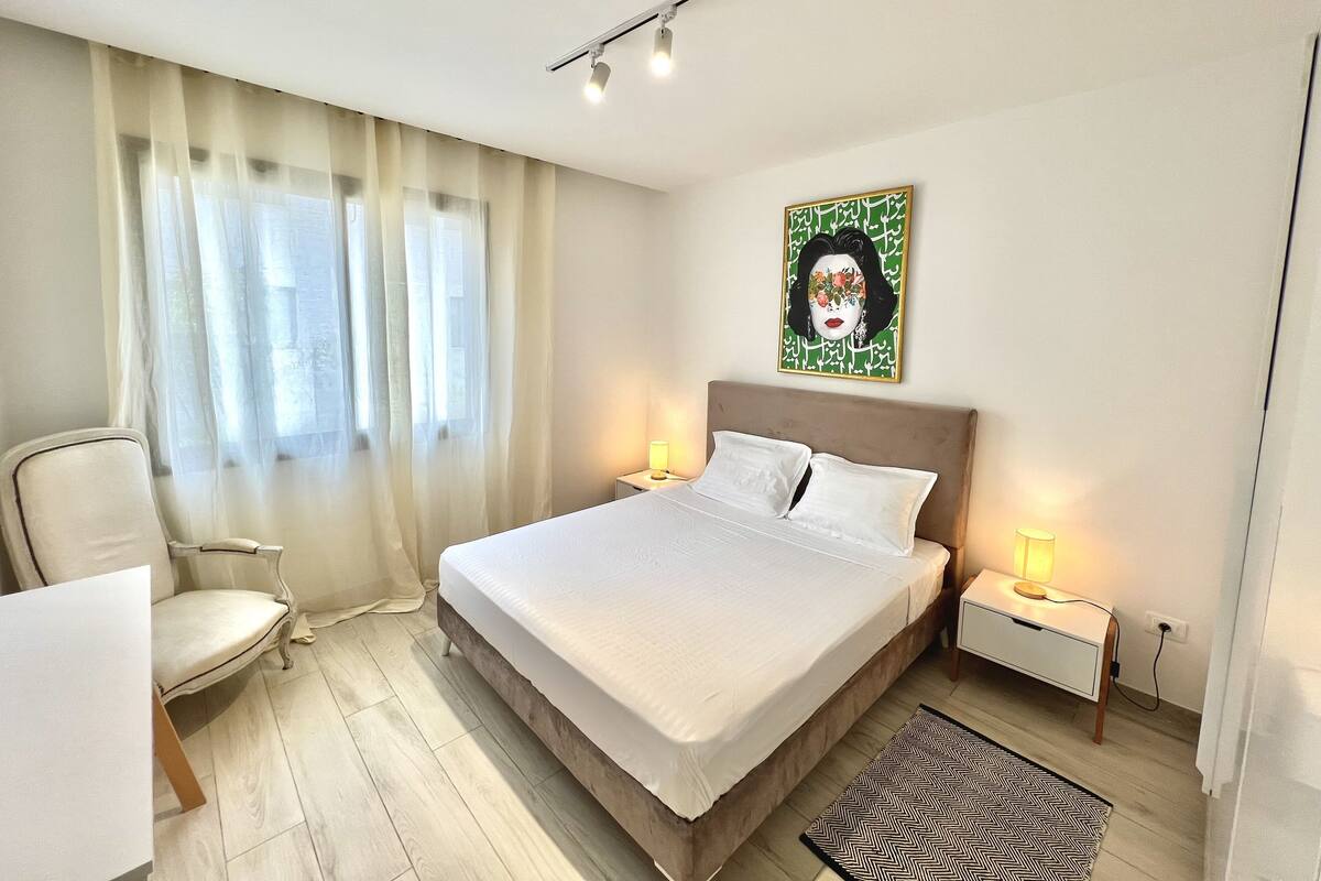 Ein Hotelzimmer mit Bett, Sessel, Nachttisch und einem Bild an der Wand.