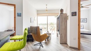 A modern, well-lit room with a dining area, a sofa, and a TV. - Gozo Escape, 2-bed Apartment in Marsalforn (Zebbug)