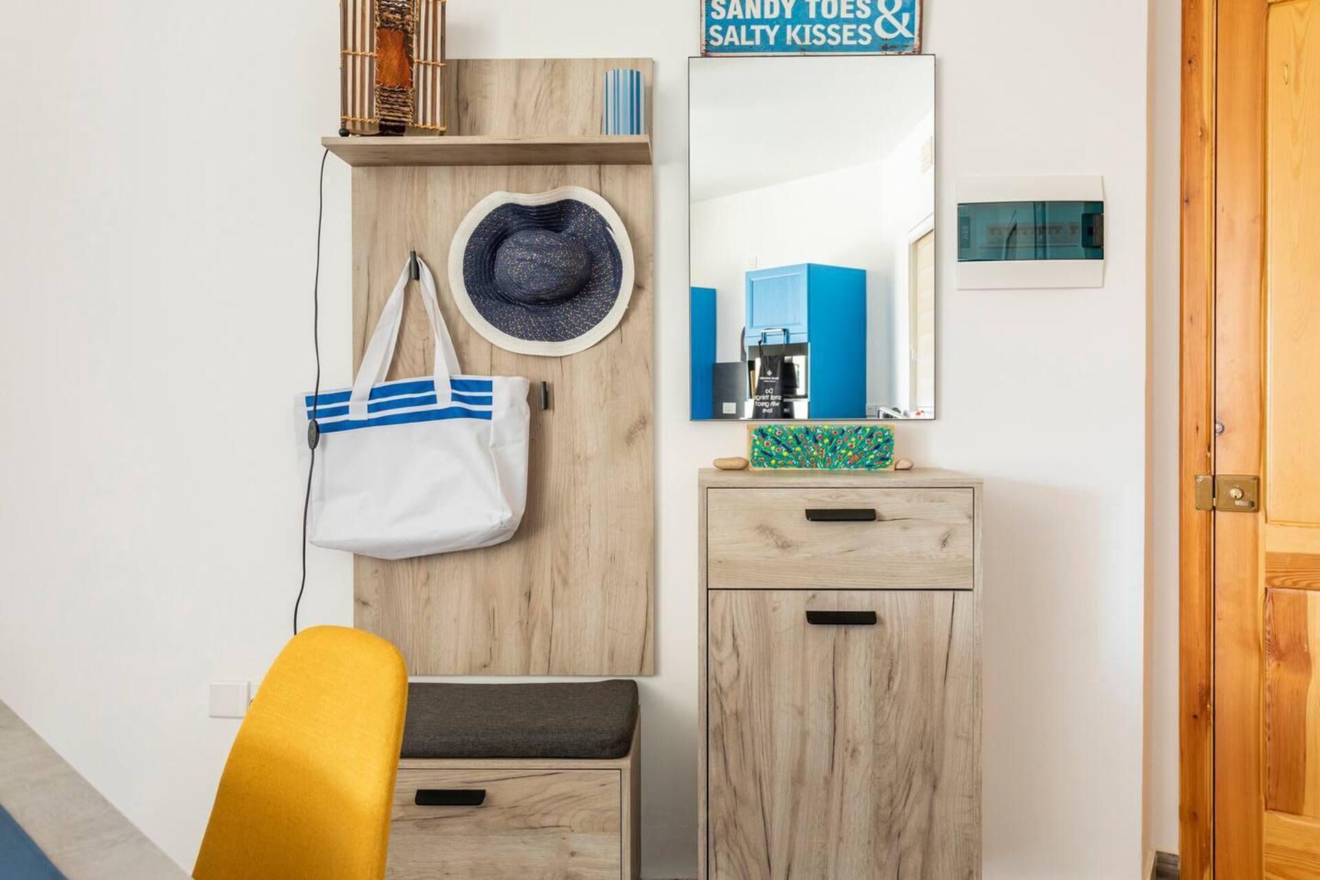 A wooden wardrobe with a mirror, a white handbag, and a hat.