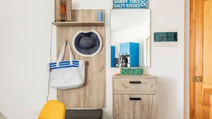 A wooden wardrobe with a mirror, a white handbag, and a hat. - Gozo Escape, 2-bed Apartment in Marsalforn (Zebbug)