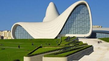 A modern architectural building with a unique curved design, surrounded by a well-maintained green lawn and a clear blue sky.
