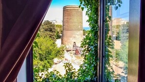 Una ventana con vistas a una estructura cilíndrica rodeada de vegetación.