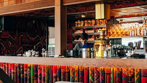 Una zona de bar con paneles de madera, una barra con diversos objetos y una pared de diseño colorido.