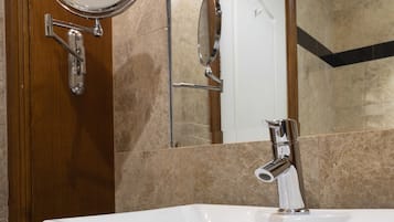 Un baño con lavamanos blanco, un espejo redondo y una puerta con marco de madera.