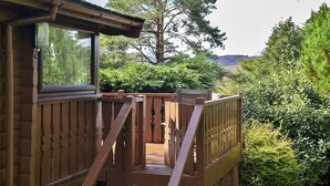 A wooden deck with a view of a large tree and a mountain in the background. - Mountain View (Trawsfynydd)