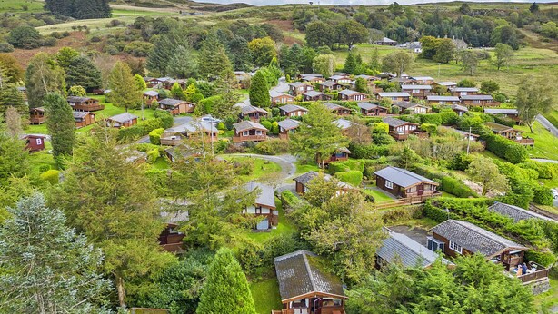 A cluster of wooden cabins surrounded by lush greenery, with a winding path connecting them. - Mountain View (Trawsfynydd)