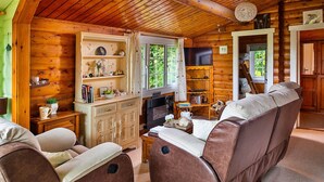 A cozy cabin interior with a wooden interior, a sofa, a fireplace, and a television. - Mountain View (Trawsfynydd)