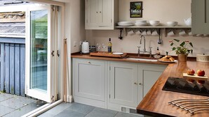 Una cocina con tragaluz, armarios blancos, encimera de madera y vistas al jardín trasero.