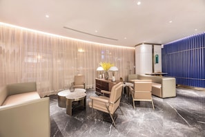 A modern hotel lobby with a seating area, a bar, and a decorative wall. - Manxin Hotel Zhangjiagang Jingang Avenue Pedesrian (Suzhou)