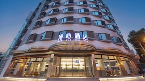 A hotel with a curved facade, large windows, and a sign in a foreign language. - Manxin Hotel Zhangjiagang Jingang Avenue Pedesrian (Suzhou)