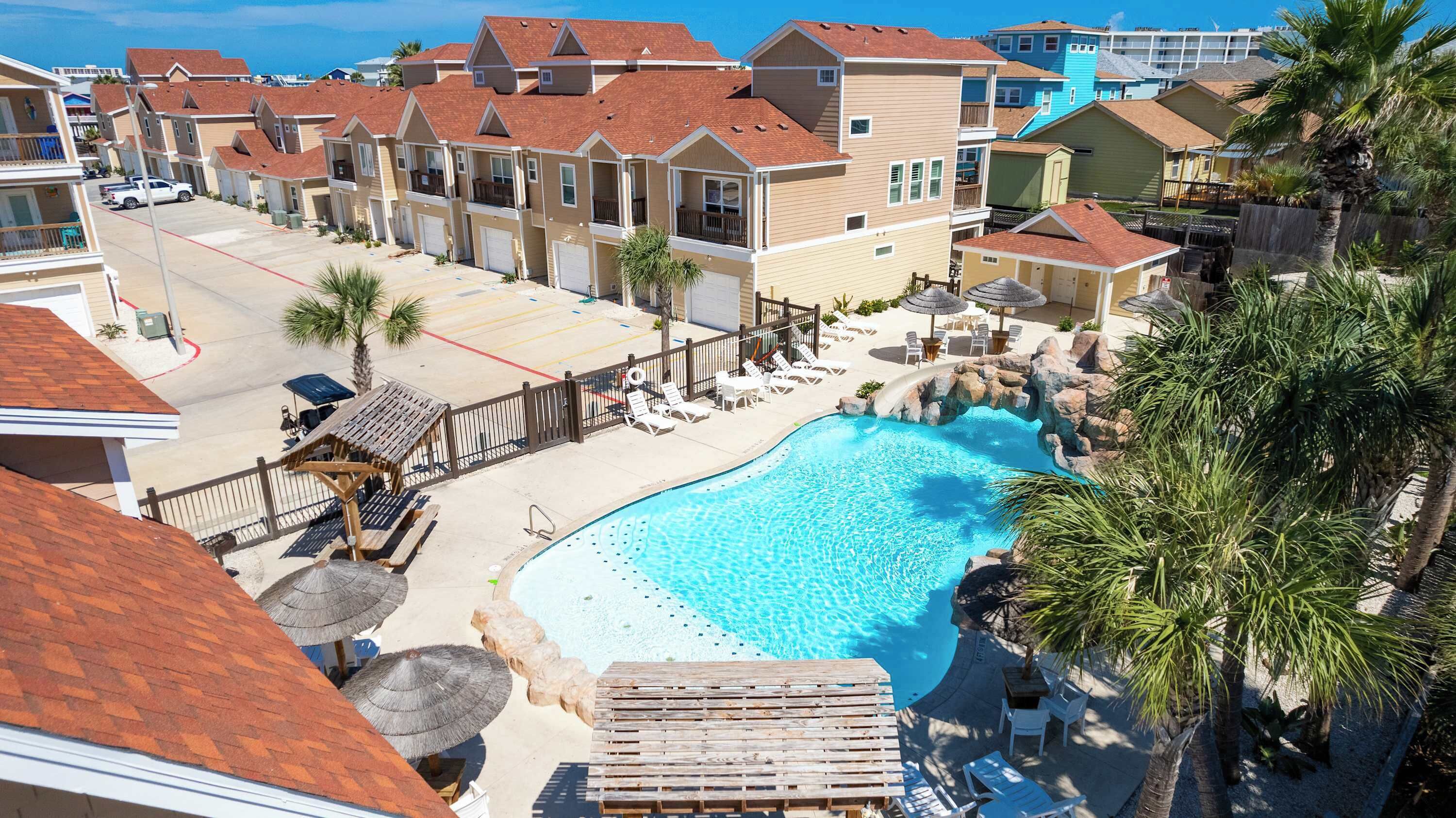 Ett semesterhotell med en swimmingpool, solstolar och utsikt över havet.