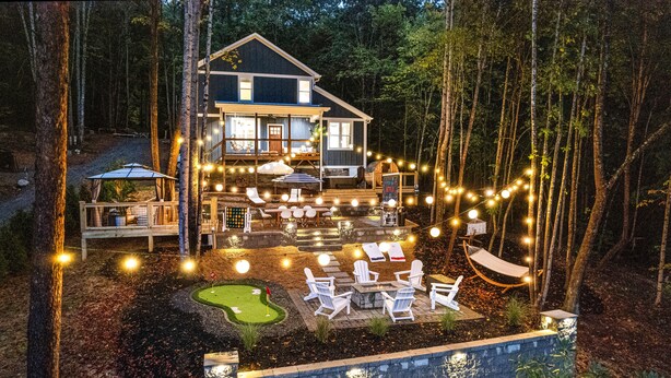 A house with a deck, outdoor seating, and string lights.
