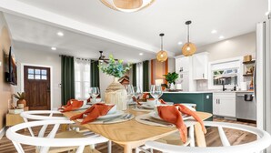 A modern dining area with a wooden table set for four, surrounded by white chairs.
