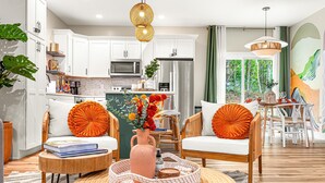 A modern living room with a sofa, coffee table, and a dining area with chairs and a table.