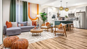 A modern living room with a grey sofa, wooden ottomans, and a patterned rug.