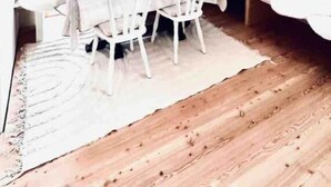 A cozy attic room with a wooden ceiling, a dining table with chairs, and a view of the outdoors through a window. - Galeriewohnung mit Ambiente (Wertheim)