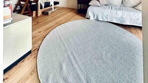 A loft bedroom with exposed wooden beams, a hanging chair, a bed with pillows, and a round rug. - Galeriewohnung mit Ambiente (Wertheim)