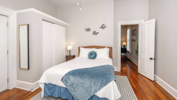 A bedroom with a bed, a nightstand, a mirror, and a wall with the words 'Faith Hope Love' written on it. - Hackberry Retreat 1 (Cincinnati)