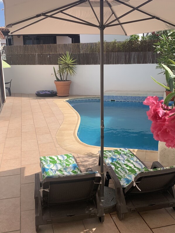 Una piscina con sillas de descanso y una pérgola.