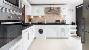Una cocina moderna con electrodomésticos de acero inoxidable, armarios blancos y salpicadero de azulejos.