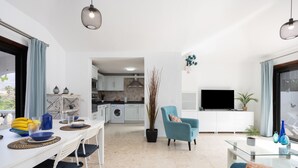 Una sala de estar moderna con comedor, cocina y televisor.