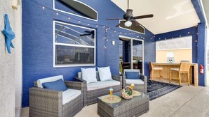 A modern outdoor seating area with wicker furniture, string lights, and a ceiling fan. - Davenport Home w/ Game Room, Home Theater, Pool (Davenport)