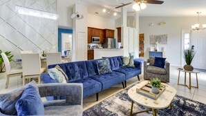 A modern living room with a blue sofa, a coffee table, and a ceiling fan. - Davenport Home w/ Game Room, Home Theater, Pool (Davenport)