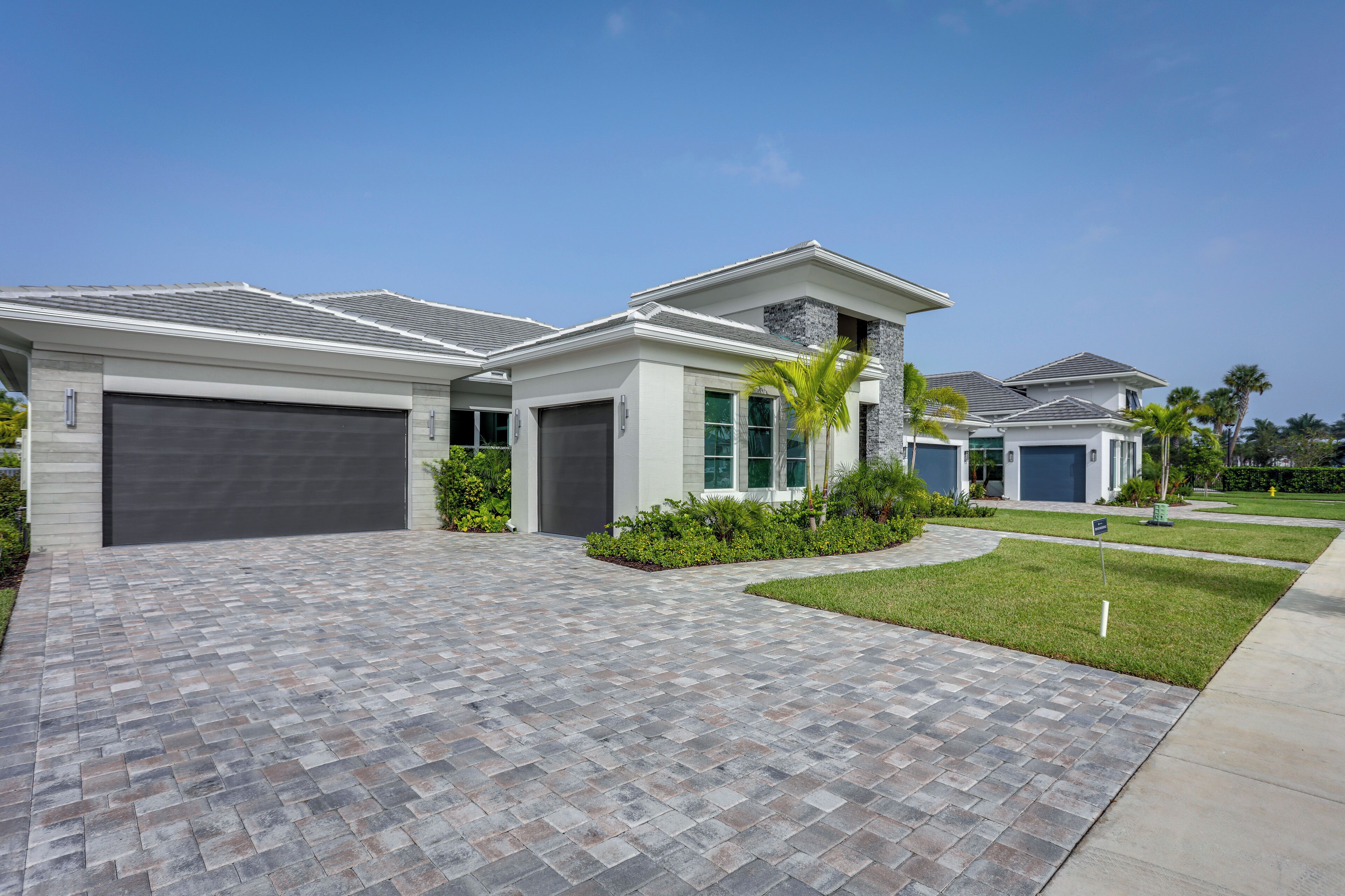 A modern two-story house with a paved driveway, a garage, and a well-maintained lawn.
