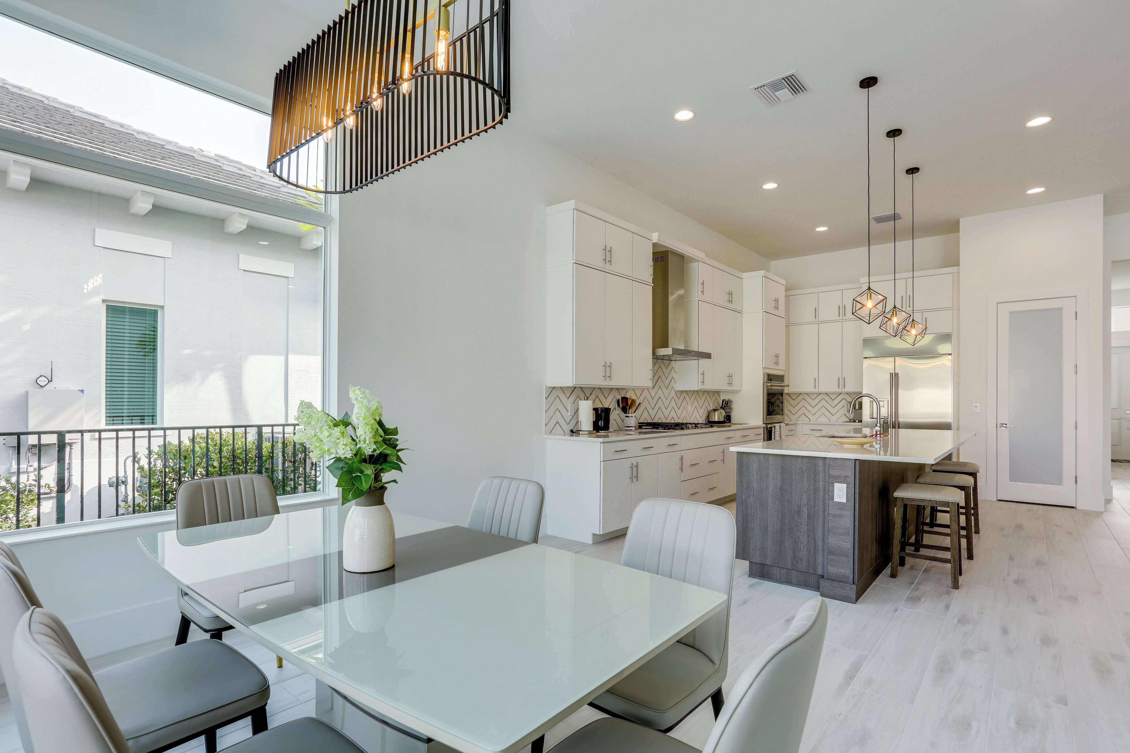 A modern kitchen with white cabinets, a central island, and pendant lighting.