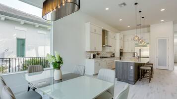 A modern kitchen with white cabinets, a central island, and pendant lighting.