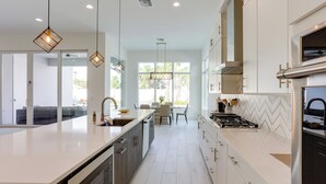 A modern kitchen with a large island, stainless steel appliances, and pendant lighting. - Private Pool & Spa: Luxe Palm Beach Gardens Home (West Palm Beach)