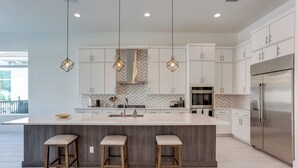 A modern kitchen with a large island, pendant lights, and stainless steel appliances. - Private Pool & Spa: Luxe Palm Beach Gardens Home (West Palm Beach)