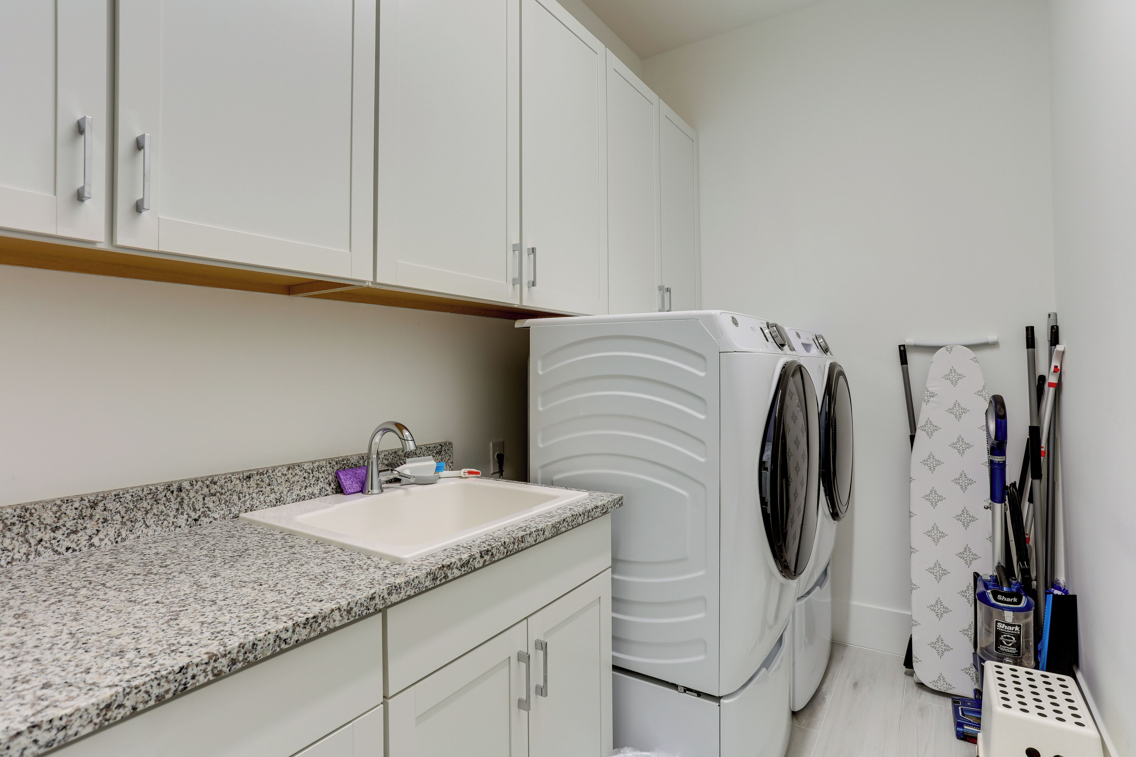 A laundry area with a washing machine, a sink, and a drying rack.