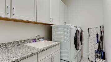 A laundry area with a washing machine, a sink, and a drying rack.